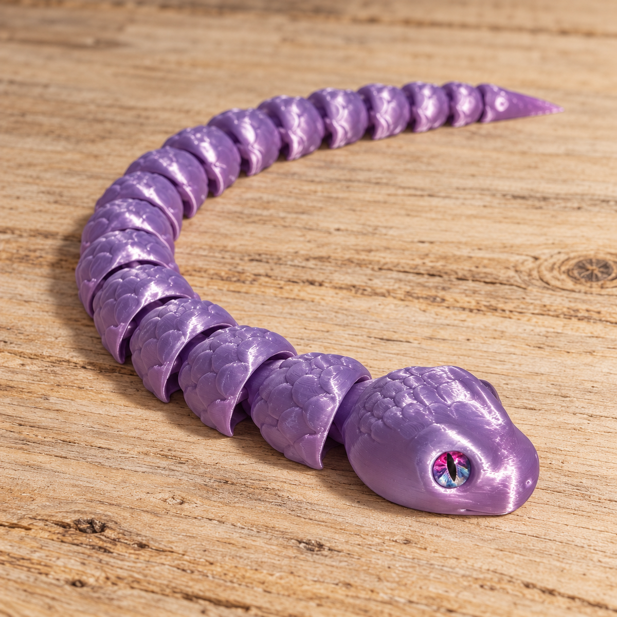 Purple articulated 3D printed snake with glass eyes on a rustic wood background