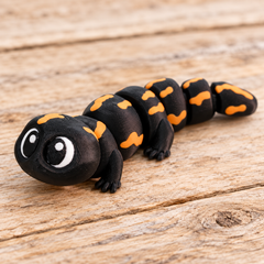 Black and orange 3D printed Flexi Salamander on a rustic wood background