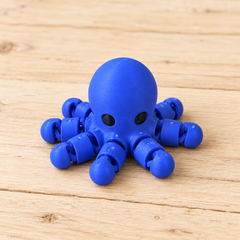 Solid blue articulated Octopus Little Critter with black eyes on light wood