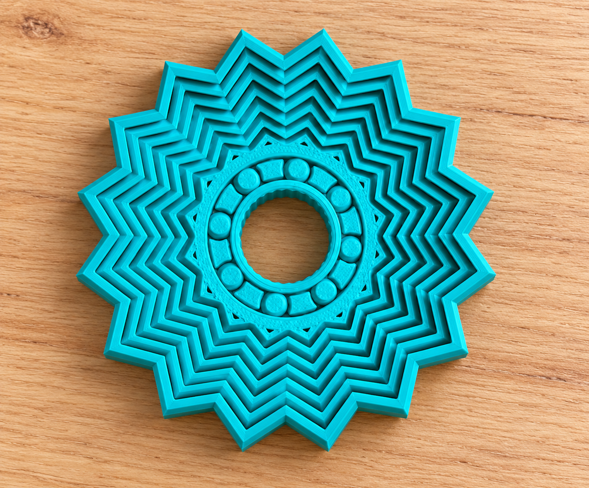 Solid teal nested Star Spinner on light wood